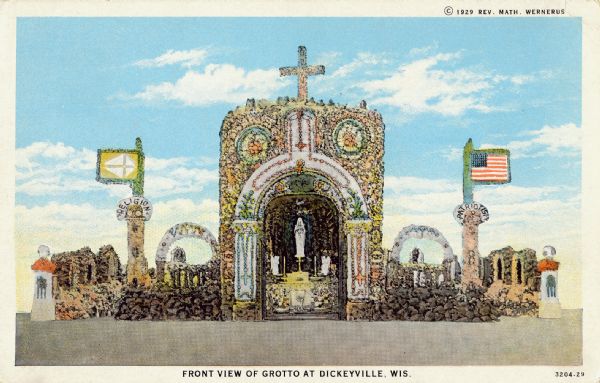 Hand-tinted postcard showing the Dickeyville grotto. Postcard caption reads: The Grotto of Christ, the King, and of Mary, his Mother, was conceived, designed, and built by a priest from thousands of pebbles, stones, shells, and corals from all parts of the world. Its beauty and originality must be seen to be appreciated. Caption reads: "Front View of Grotto at Dickeyville, Wis."
