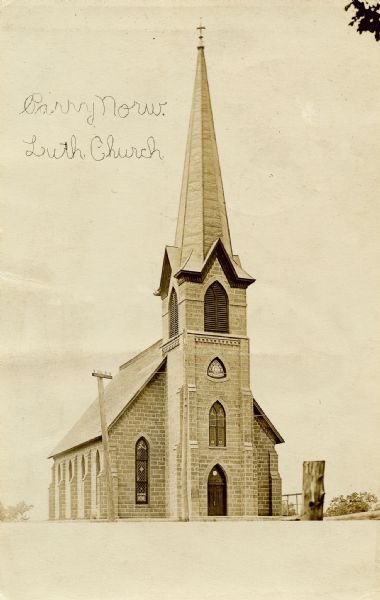 Exterior of Perry Lutheran Evangelical Church, which is misspelled in the caption as "Parry Norw. Luth. Church." The photograph was taken some time between 1881, when the steeple was added, and 1915, when a chancel was added to the church.