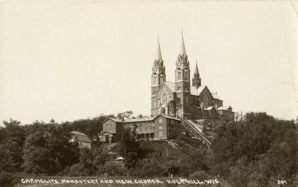 Postcard showing the Carmelite monastery and church at Holy Hill. The postcard identifies this as the "new church," which suggests the photograph was taken shortly after the church's completion in 1930. Caption reads: "Carmelite Monastery and New Church, Holy Hill, Wis."