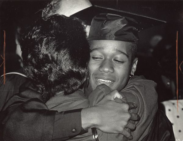 A high school student in cap and gown is hugging a woman. Caption reads: "END OF THE ROAD — Jason Boyd hugged the mother of a fellow graduate after Riverside High School's graduation ceremony at the Auditorium. Boyd joins about 3,700 Milwaukee Public Schools 1989 graduates, some of whom received diplomas Wednesday. Ceremonies continue tonight."