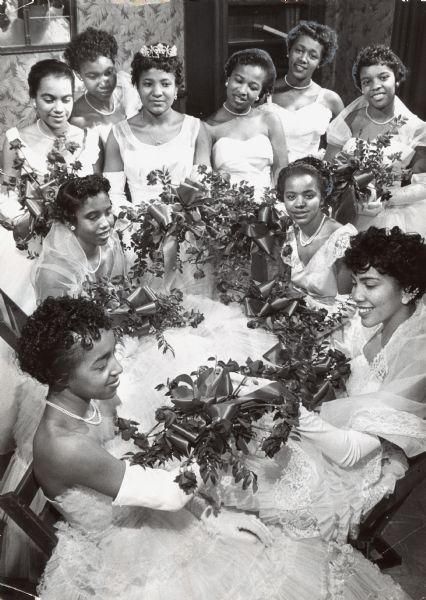 Ten young women in formal gowns are holding bouquets and posing together. Caption reads: "Debutantes were the guests of honor at the 24th annual ball of the Cosmopolitan club at Prince Masonic hall, 1218 W. North Av., over the week end. Among those present were (clockwise, from left) Misses Edris Washington, 2830 N. 10th St.; Mae E. Washington, 2902 N. 10th St.; Marian Johnson, 2471 N. Palmer St.; Nancy Baldwin, 807 W. Clarke St.; Estelle Wilson, 2821 N. 2nd St.; Marva Hayes, 2758 N. 7th St.; Betty Grays, 2638-A N. 13th St.; Yvonne Travitt, 1854 N. 13th St., and Marilyn Williams, 2638-A N. 7th St."