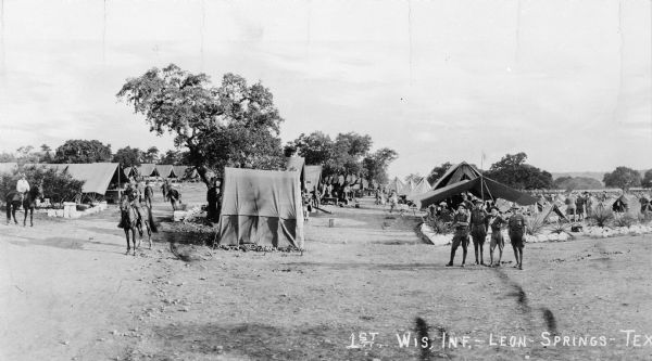 Camp of the 1st Wisconsin Infantry at Leon Springs, Texas. Soldiers are standing near tents, with some men sitting astride horses.
