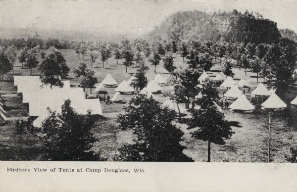 Elevated view of tents at Camp Douglas. A few soldiers are among the tents. A large, rocky hill is in the background on the right. Caption reads: "Birdseye[sic] View of Tents at Camp Douglass [sic], Wis."