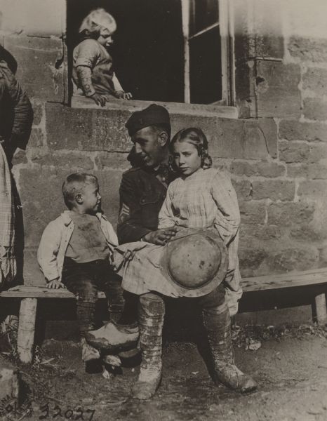 Sgt. J.W. Killigrow, 311th Ambulance Co., 78th Division, socializing with French children who remained in Authe during the German occupation.