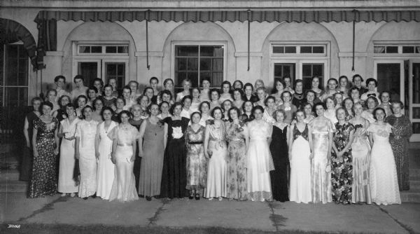 Group portrait of women wearing full length gowns standing together in front of a building. Caption reads: "Phi Delta Gamma graduation party (?) taken at Maple Bluff Golf Club House, Aug 20 1936."