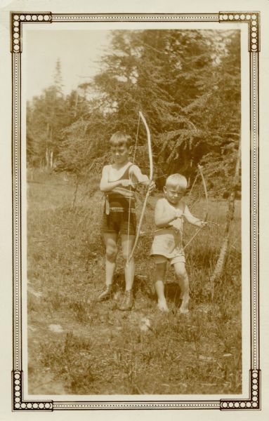 Two boys posing with bows and arrows.