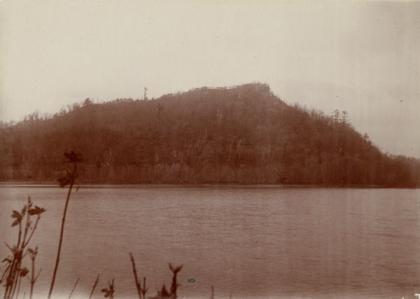 View of a tree-lined mountain across a body of water. Caption reads: "Trempealeau Mountain from across the bay."