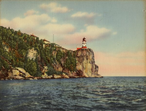 Oversized "Colortone" postcard view across water towards the Split Rock Lighthouse from the waterline, looking up the bluffs, with other buildings along the left. Postcard caption reads: "X-501 — Split Rock Lighthouse on North Shore of Lake Superior. The rugged beauty of Lake Superior's north shore — stretching 150 miles from Duluth to the Canadian border — is world famous. This scenic highway unfolds a thrilling ever-changing panorama of primitive forests, rushing streams, hills and shore line. Picturesque Split Rock Lighthouse, aids Great Lakes navigators approaching the Duluth Harbor and warns them of the dangers of this rocky promontory."