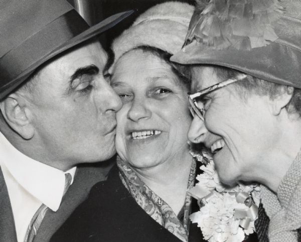 A woman is smiling as a man kisses her; another woman on the right is smiling. Caption reads: "It was a happy reunion Saturday night for Mrs. Augusta Svajonovsky, 60, of Buenos Aires, Argentina, with a brother she had not seen in 39 years and a sister she last saw 52 years ago. She was greeted at Gen. Mitchell field by John Butula, 1823 N. 26th St., and Mrs. Mary Boettcher, 3821 W. Hampton Av."