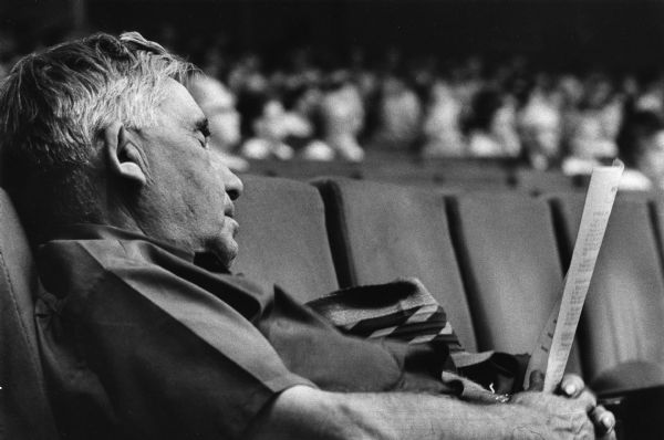 A man is leaning back in a theater seat with his eyes closed, holding a paper bulletin. Caption reads: "ENJOYING THE CONCERT — Arthur Van Dale closed his eyes as he listened to waltzes from Richard Strauss' 'Der Rosenkavalier' during the Milwaukee Symphony Orchestra's first Senior Citizen concert of the season. About 1,000 attended the free concert in Uihlein Hall at the Performing Arts Center. The orchestra was conducted by Kenneth Schermerhorn. Van Dale lives at 1419-B N. 22nd St."