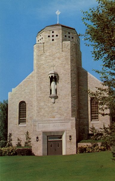 View across lawn towards the front of a church, which has a bell tower, and a statue in a niche above the entrance. Caption on back reads: "<b>St. Joseph's Catholic Church</b>, top of Main St. hill, is the inspirational sight which first meets the eye as you enter the city of Black River Falls. The stately, impressive structure warmly invites all who view it."