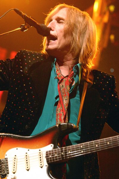 Tom Petty singing into a microphone and playing a Fender guitar during a performance at the Alliant Energy Center with his band Tom Petty and the Heartbreakers.