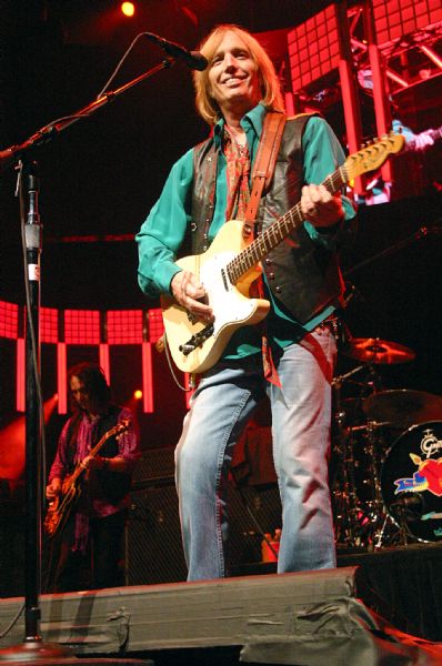 Tom Petty smiles as he plays guitar during a performance at the Alliant Energy Center with his band Tom Petty and the Heartbreakers. Guitarist Mike Campbell is behind him.