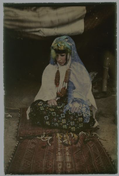 Autochrome portrait of a Tuareg woman sitting on a blanket.