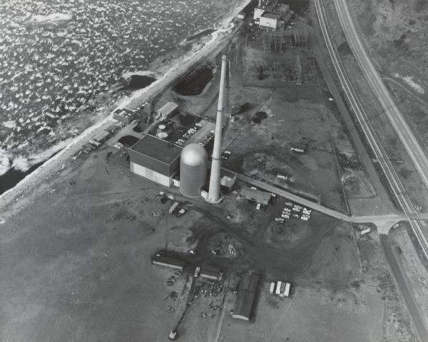 Aerial view of what is identified by the caption as a "Nuclear power plant near Victory (Vernon Co.), Wis." This would be the La Crosse Boiling Water Reactor — also known as Genoa Unit 2. The main buildings and smokestack are visible, as well as a few outbuildings. The Mississippi River shoreline is at top left.