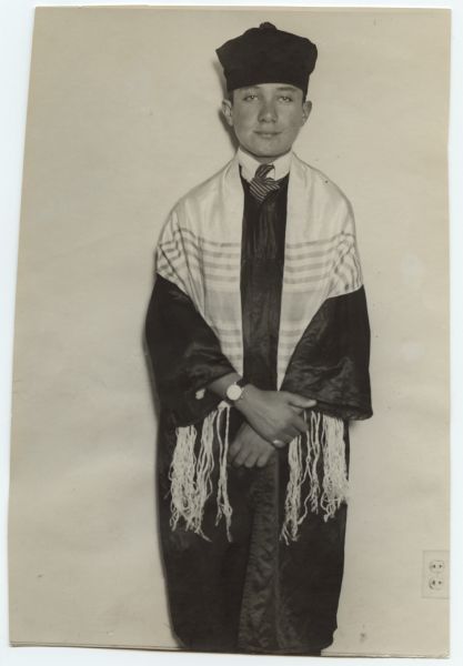 A boy is standing and posing wearing a tallit and a kashket, as well as a robe, tie, and wristwatch. Caption reads: "Cantor in City. A 13-year-old cantor will perform and say the prayers at the Friday evening and Saturday morning services at the Congregation Degel Israel Anshe Roumania temple at Eleventh and Vine Sts. He is Harry Schlomowitz, who came from Cromsk, near Warsaw, Poland, a little more than a year ago, and made his home in Chicago, where he has been studying voice culture under Prof. Max Zelekovitz. Harry was discovered as cantor when he was heard singing Polish songs in his home by members of the Chicago Jewish temple."