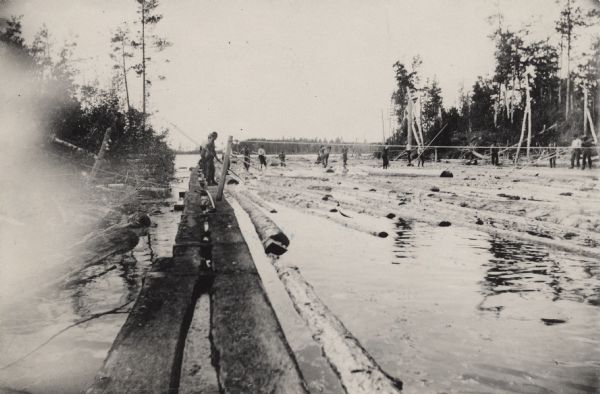 Log sorting operation on a river in Northern Wisconsin. Men stand on floating logs and maneuver them using cant hooks.