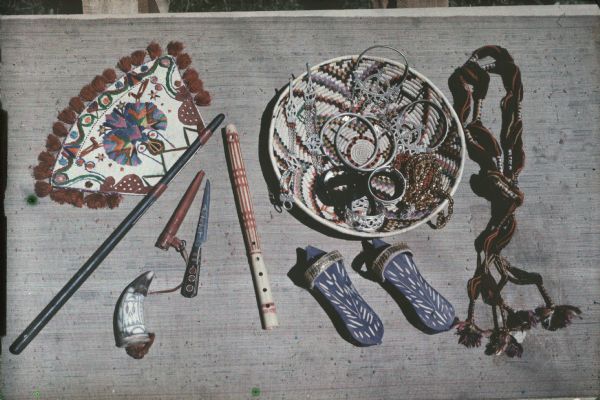 Autochrome documentary display of several colorful objects collected from Tuareg people by Alonzo Pond on his Algerian expedition. Included are a bowl, a knife, a flute, several bracelets and earrings, among other various items. 