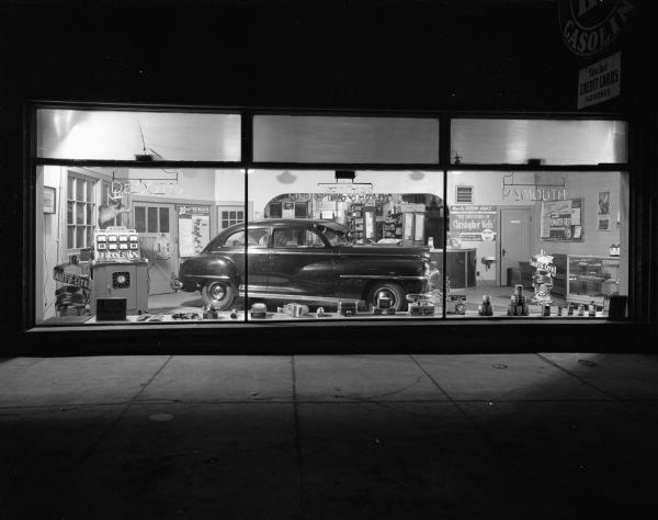 Night view of the exterior of the Schulz Garage. A DeSoto Fluid Drive automobile is seen inside the showroom through the large, plate glass windows.