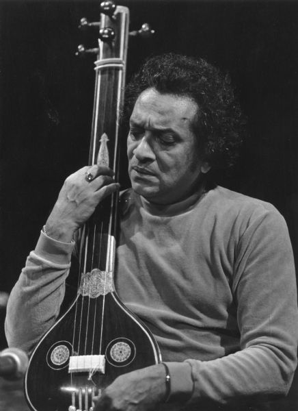 Ravi Shankar playing an Indian instrument while performing in concert.