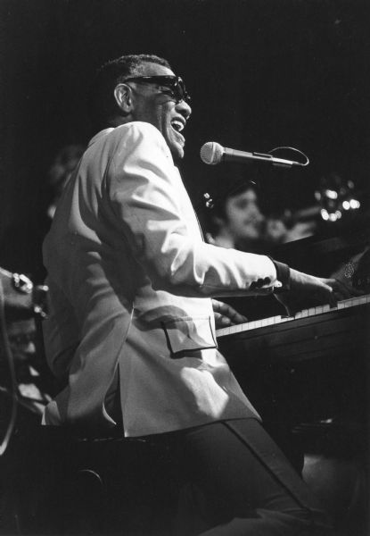 Ray Charles singing and playing piano during a performance. 