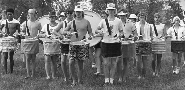 The Madison Scouts Drum and Bugle Corps playing outdoors. The drummers' casual attire suggests they are rehearsing rather than performing. 