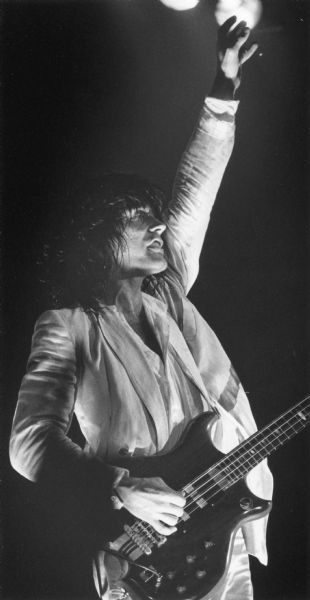 Bassist Tom Petersson raising a hand during a performance with his band Cheap Trick.