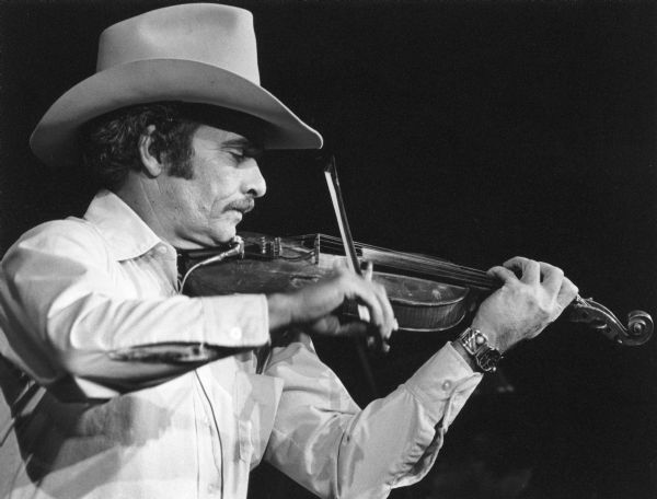 Close-up of musician Merle Haggard playing violin during a performance.