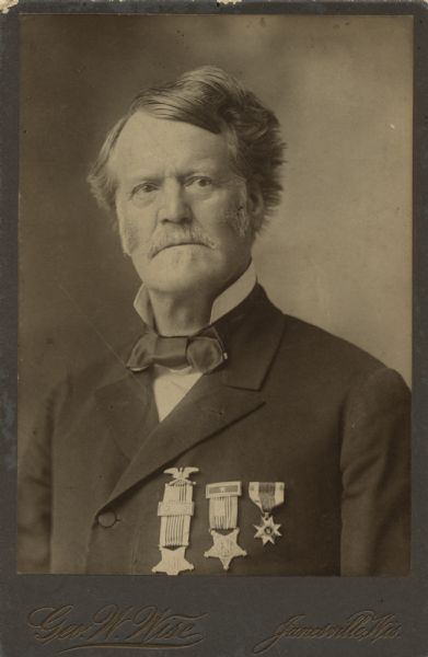 Quarter-length portrait of a man wearing a suit and tie, with three medals pinned to his chest. This is Dr. Joseph Bellamy Whiting, who was a physician in Janesville. He was the commissioned surgeon to the 33rd Wisconsin Volunteer Infantry Regiment during the Civil War. In 1875 he was unanimously appointed president of the Wisconsin State Medical Association. He was also on the Board of Trustees for the State School for the Blind. In 1889 President Cleveland appointed Dr. Whiting to a commission addressing the Chippewa [Ojibwe] Indians. Dr. Whiting died on March 27, 1905.