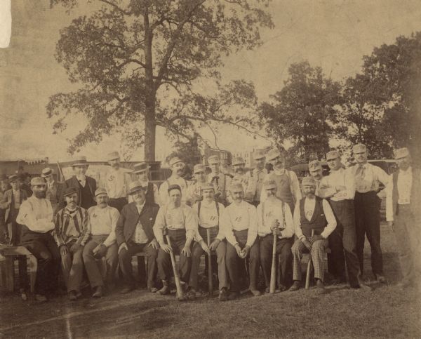 Group portrait of men posing outdoors; a few of the men are holding baseball bats or catcher's mitts. The photograph has a number written on each man to identify them. Caption reads: "Racine, Wis. August 1, 1890. Baseball teams composed of local lawyers and physicians. Standing, left to right: Kitto, Dr. Pope, Dr. Meachem, Dr. Eagan, Smirding (?), Fish, Lee, Nelson, Cooper, Gittings, Palmer, Owens, Juda (h?). Seated, left to right: Dr. Meachem, Jr., Hand, Winslow, Dyer, Kearney, Dr. Keech, Dr. Wheeler, Dr. Duncombe, Dr. Shoop. Photo by Easson and Co., Racine, Wis."
