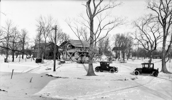 Construction in the Lakewood neighborhood. There are two cars parked in the snow on the right.