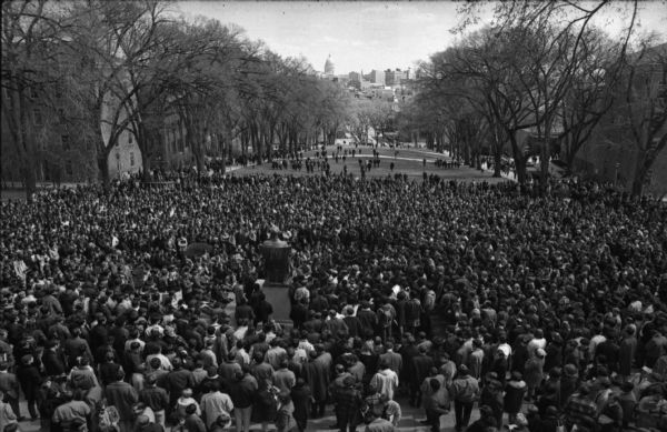 Elevated view of a large crowd gathered at the top of Bascom Hill in reaction to the assassination of Dr. Martin Luther King, Jr. The Wisconsin State Capitol is in the distance.