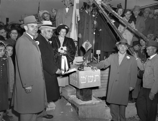 As the cornerstone of Beth Israel Center was lowered into place, representatives of the oldest Madison Jewish congregation participated in the ceremony. They are (from left) A.J. Rosenberg, Emanual Simon, Mrs. Meril Stein, and A.J. Sweet. Gus E. Widen, mason superintendent for Vogel Brothers, is at the extreme right. The metal box below the cornerstone contained membership lists and other documents. The Hebrew inscription reads 5709, the Jewish calendar year.