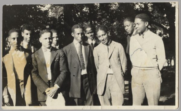 Nine young men are posing together, most of them wearing suits. Caption reads: "Elite of the younger set in Madison. Ted second from left, Buck Weaver football third from right."