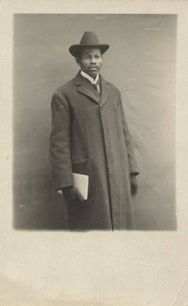 Three-quarter length portrait of a man in long coat and hat, holding what appears to be a book. Caption reads: "Uncle Ben Pierce, oldest brother of Samuel (1 of 11 children); This Photo is for mama."