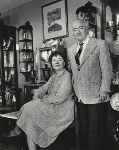Portrait of a man and woman posing together; the man is standing and the woman is sitting. Behind them are several display cases with various items, some of which appear to have tags attached. Caption reads: "OPENING A DECORATIVE arts shop was, for Eileen and William Liebman, a more attractive idea than wintering in Florida. They sold their condominium there and opened a shop, Circa Unlimited, Inc., on E. Silver Spring Dr., Whitefish Bay."