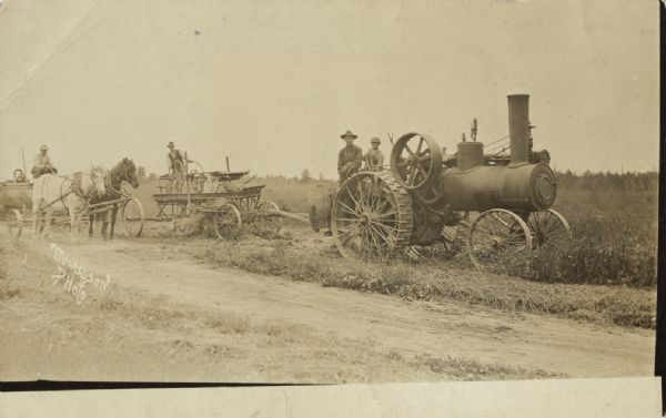 Four men are posing atop different carts, one of which is hitched to horses, and an engine. Caption reads: "This is me on the engine I worked on this summer before I worked for Austin Knutson. I will thank you for the cards again and again."
Additional caption reads: "Early road work in Barronett. The engine driver is one of the Nelson brothers formerly of Timberland."