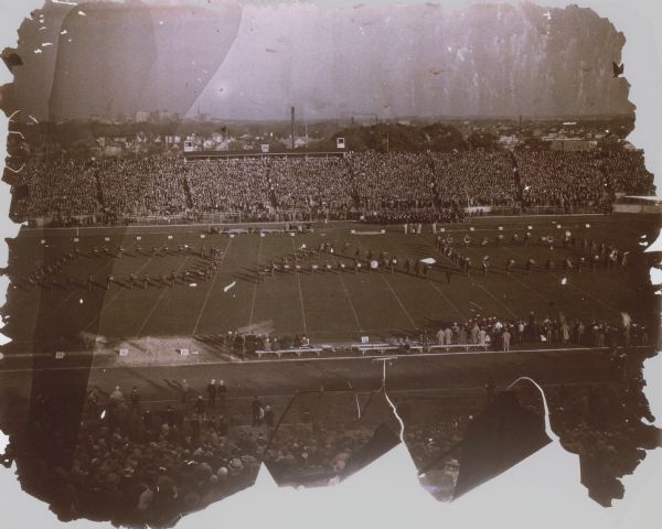 Elevated view of the University of Wisconsin marching band in formation spelling "DAD" at Camp Randall Stadium at the Wisconsin-Iowa football game. In the distance is the Madison skyline with the Wisconsin State Capitol.