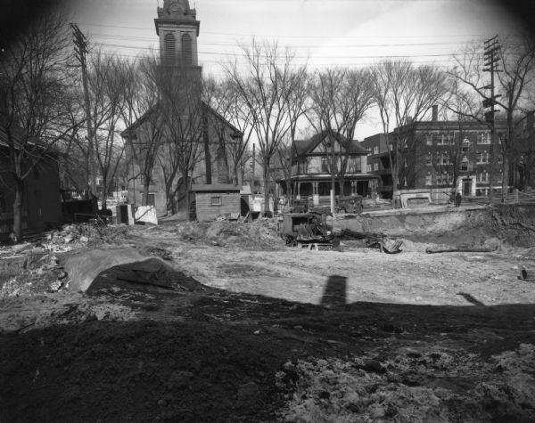 Orpheum Theater under construction, 216 State Street, looking west. Also shows Holy Redeemer Catholic Church, 128 W. Johnson Street, Holy Redeemer Rectory, 120 W. Johnson Street, and Windemere Apartments, 118 W. Johnson Street.