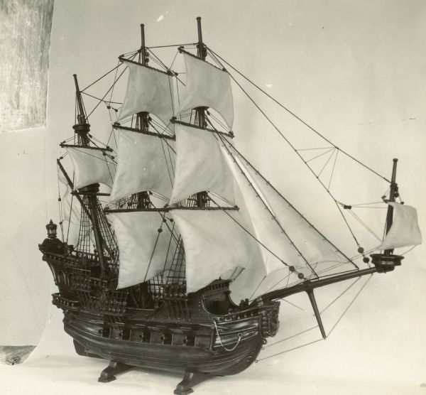 Model galleon in front of backdrop with projection reels in the background.