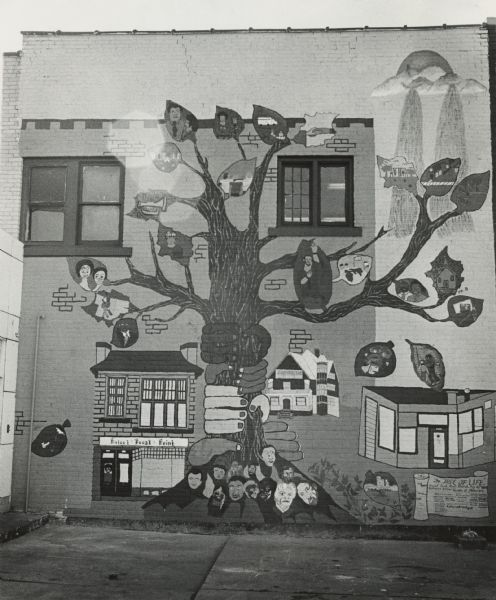 Mural on the side of a building, depicting hands of different colors grasping a tree. The tree has many faces at its base and various scenes on its leaves. Caption reads: <b>"'TREE OF LIFE'</b> — A mural at Project Focal Point, 811 W. Burleigh St., was an undertaking of Milwaukee area Girl Scouts and young workers employed by Inner City Youth Service Agencies under the direction of Lovenia Johnson, a member of the Focal Point staff. The tree of life illustrated good things the children would like to see in the city."