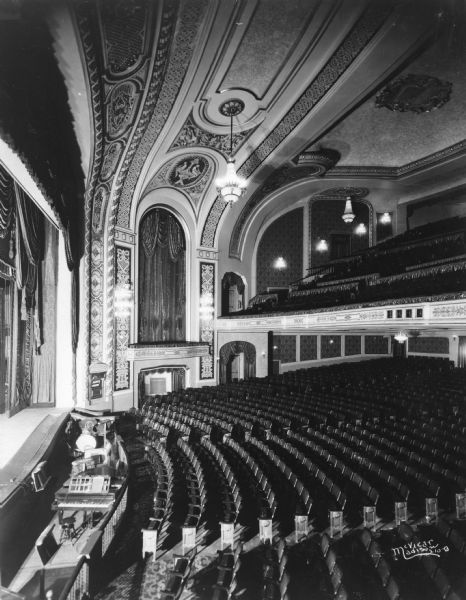 Elevated view from left side of stage of the new Orpheum Theater interior, showing the stage, orchestra pit, auditorium and balcony. A sign on the right side of the stage near the steps reads: "Nobody's Widow."