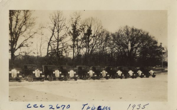 A row of trucks are parked in a lot with trees in the background. The caption identifies the trucks as belonging to CCC 2670, the Madison-based 2670th Company of the Civilian Conservation Corps. They were responsible for the restoration of Curtis Prairie, among other projects.