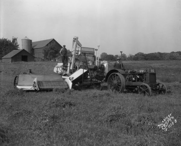 Two men operating a Nichols & Shephard combine tresher and Hart Parr tractor.