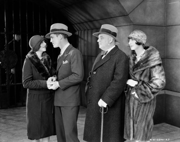 Eleanor Griffith is looking into the eyes of Chester Morris, while Harry Stubbs and Mae Busch are looking on. They are standing outside a prison gate in a scene from the 1929 film "Alibi." 