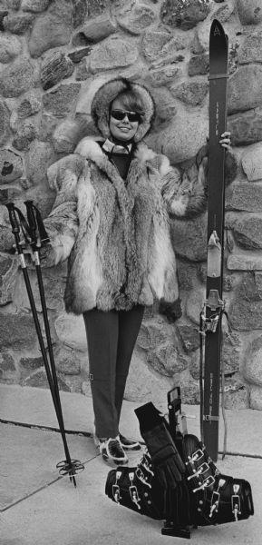 A woman is posing in a fur coat and ski gear. Caption reads: "DONNA DROTT DISPLAYS HER FAVORITE ENSEMBLE..."