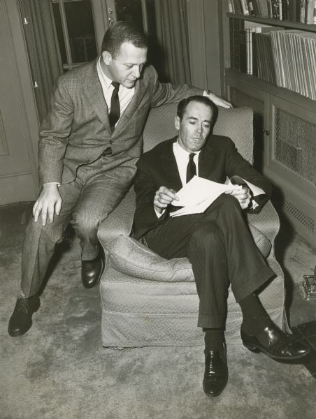 Henry Fonda is sittting in a chair, and Reginald Rose is sitting on the arm of the chair. The two men are looking at a script.