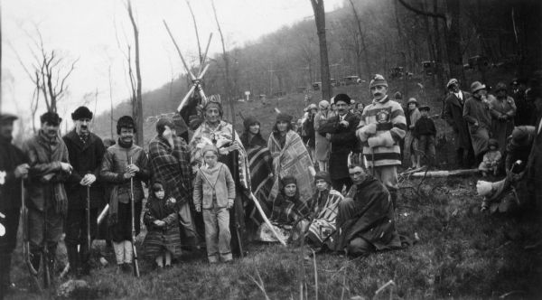 A large group of actors posing together outdoors while in costume. They are participants in a reenactment of a ceremony in which Nicolas Perrot claimed the territory of the upper Mississippi River for France at Fort St. Antoine. 