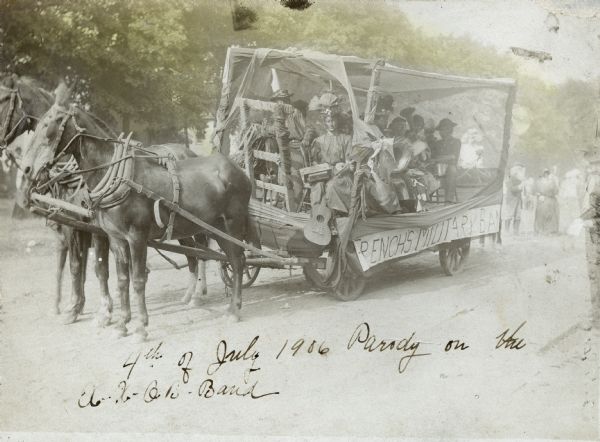 A group of people on a horse-drawn wagon. They are holding or playing instruments, and appear to be wearing blackface makeup. Text written at bottom reads: "4th of July 1906 Parody on the [?] Band." A sign along the side of the horse-drawn  wagon reads: "French's Military Band."