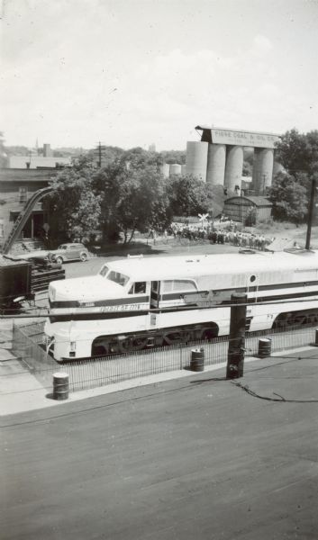Elevated view of the Freedom Train. A line of people are behind the locomotive. In the background are the storage tanks for Fiore Coal & Oil Co.